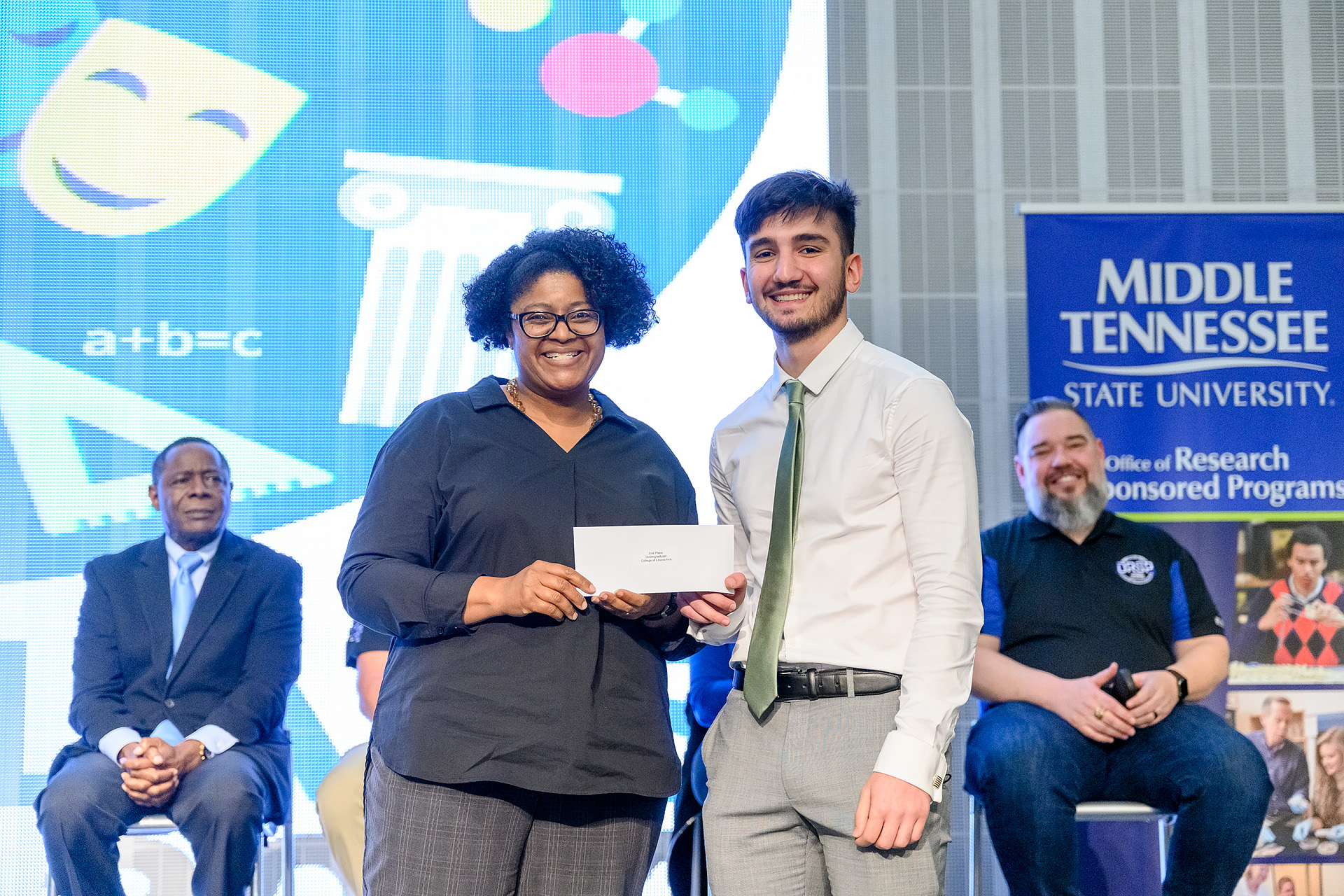 Student, Saman Kittani, is presented with a check from the dean of the College of Liberarl Arts for his Scholar's Day research presentation. 