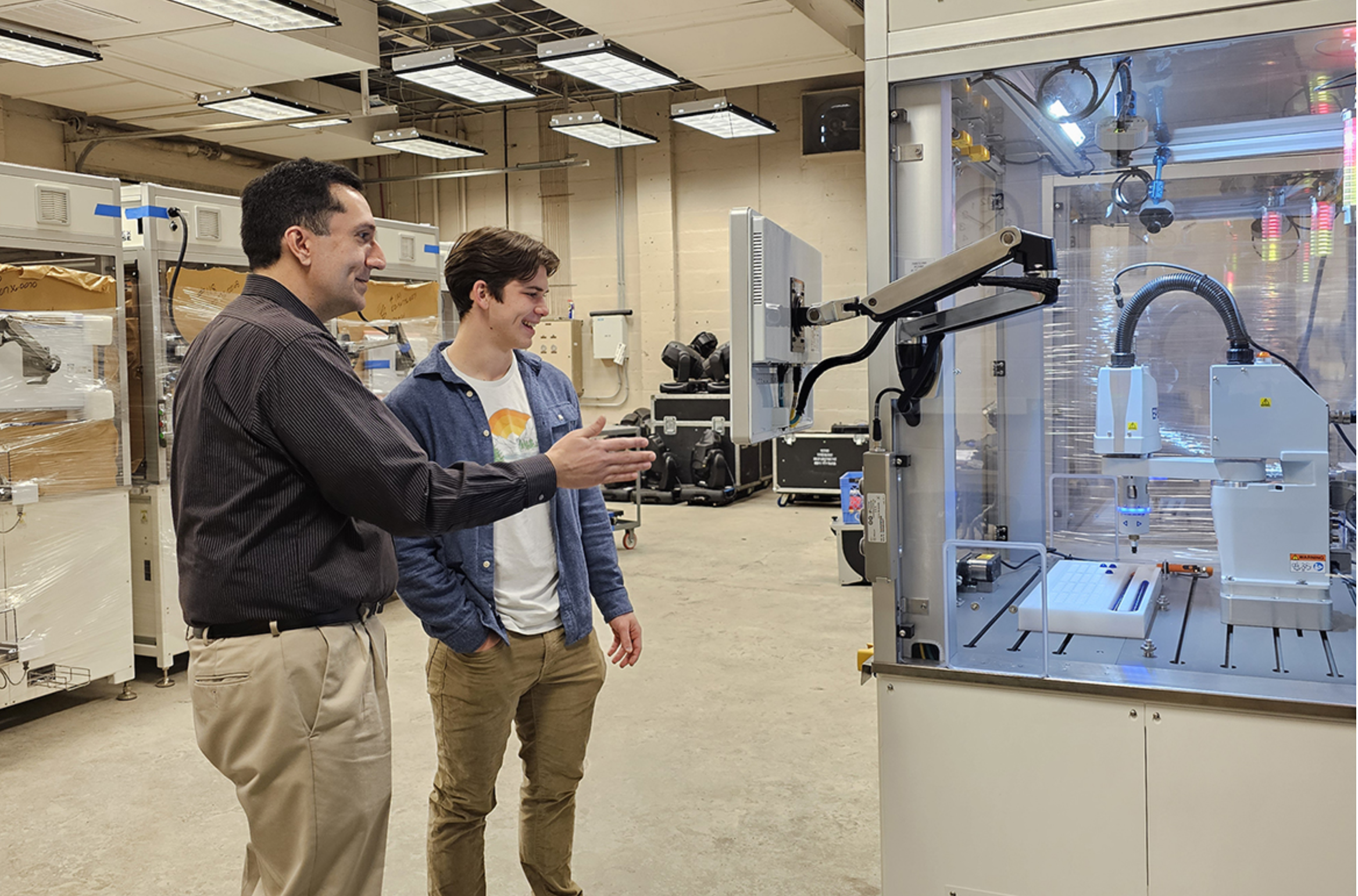 Middle Tennessee State University junior mechatronics engineering major Samuel Apigian, right, and Engineering Technology lecturer Antonio Saavedra are pictured next to robotics equipment inside a Voorhees Engineering Technology laboratory earlier this semester on the MTSU campus. Apigian is heading to Germany this summer after being awarded the highly competitive DAAD RISE scholarship where he will be interning at Technische Universität Dresden. (MTSU photo by Robin E. Lee)